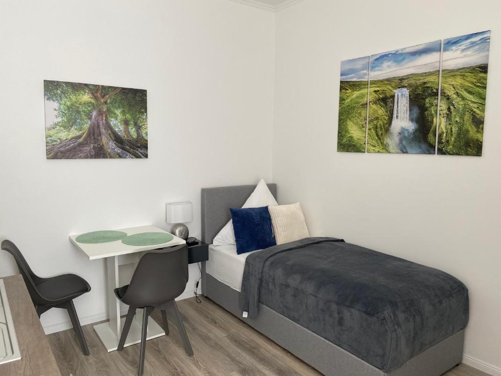 a bedroom with a bed and a desk and two paintings at Prime Host Smart Apartments in Karlsruhe