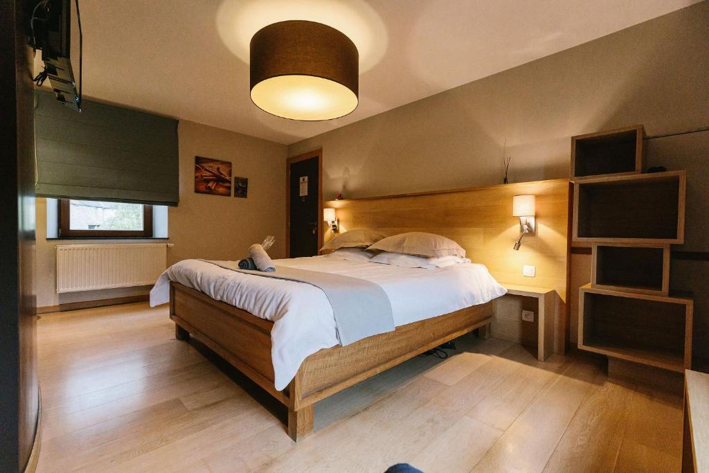 - une chambre avec un grand lit et une tête de lit en bois dans l'établissement B&B L'Echappée Belle, à Falaën