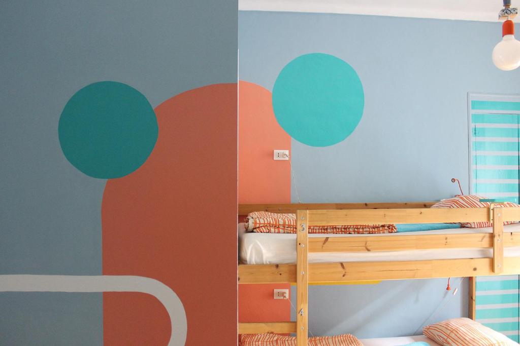 Bamboo Eco Hostel في تورينو: غرفة نوم مع سرير بطابقين مع جدران برتقالية وزرقاء