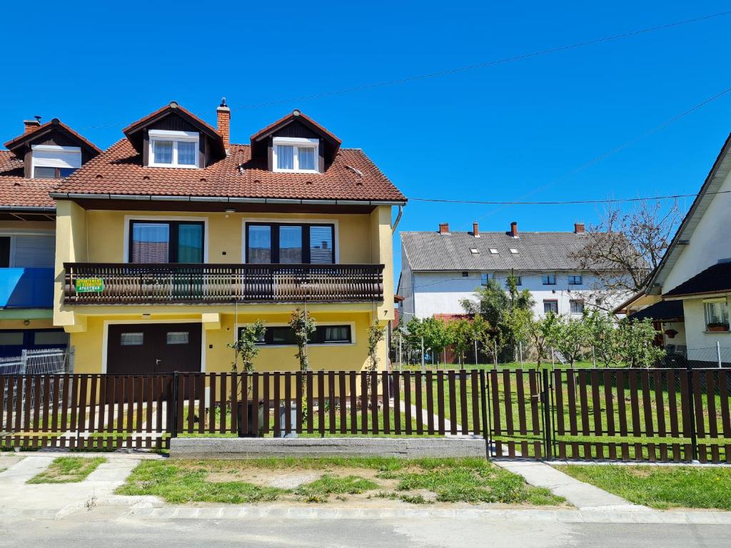 una casa amarilla con una valla delante de ella en Gyöngyvirág Apartman Lenti en Lenti