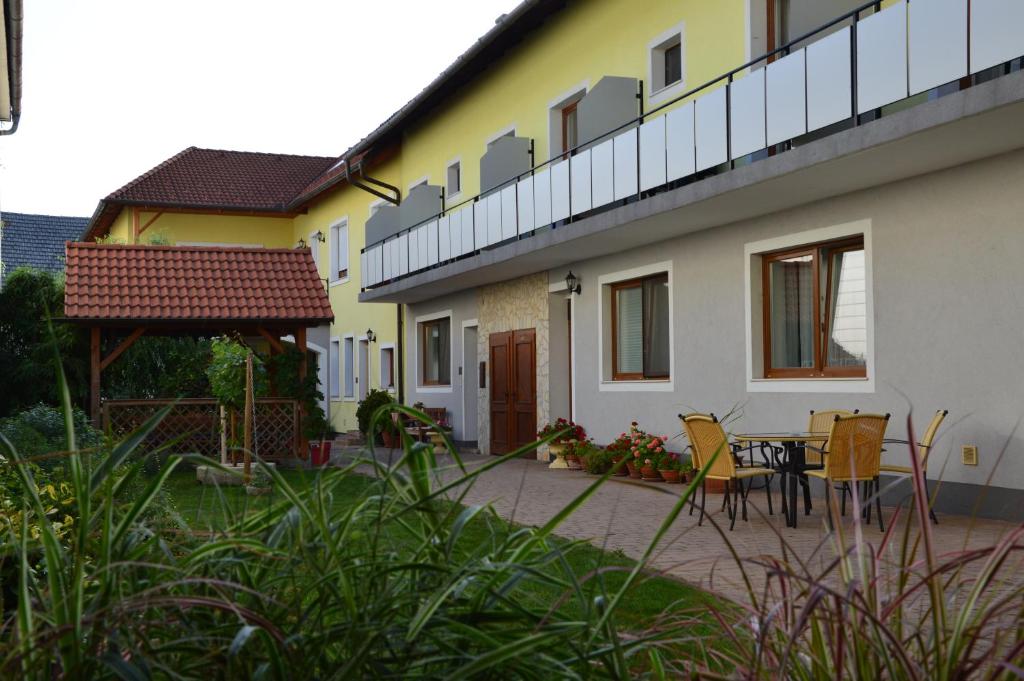 ein Haus mit einer Terrasse, einem Tisch und Stühlen in der Unterkunft Weingut & Gästehaus Dombi Weiss in Podersdorf am See