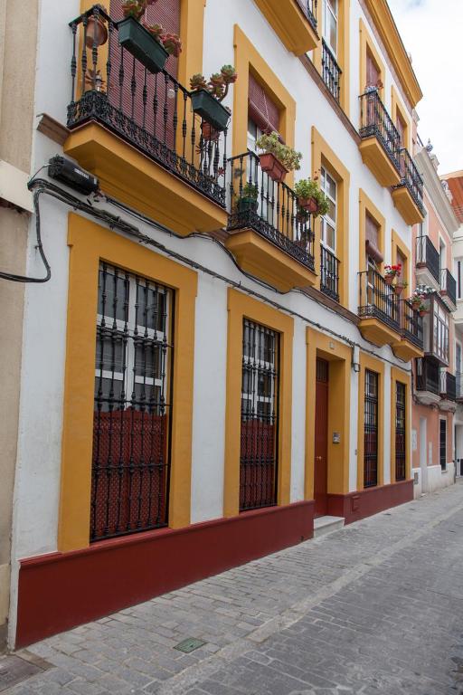 żółto-biały budynek z oknami i balkonami w obiekcie Precioso Apartamento Sevilla Centro w Sewilli