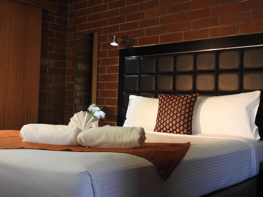 um quarto com uma cama com duas toalhas em Pooraka Motor Inn em Mawson Lakes