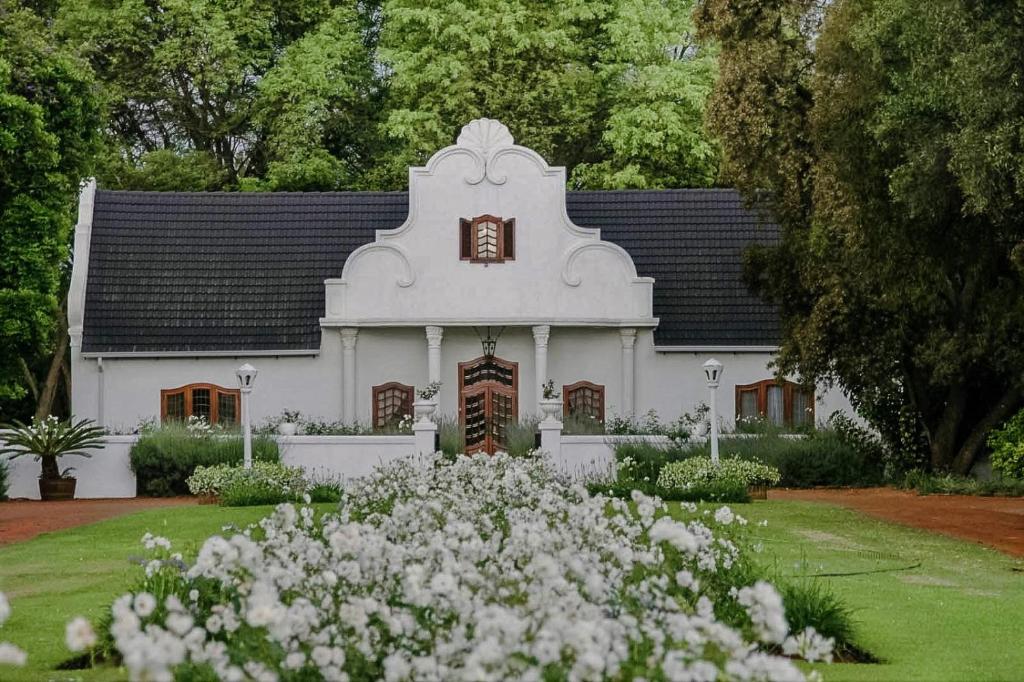 a white house with a clock tower and white flowers at Morgenzon Estate in Pretoria