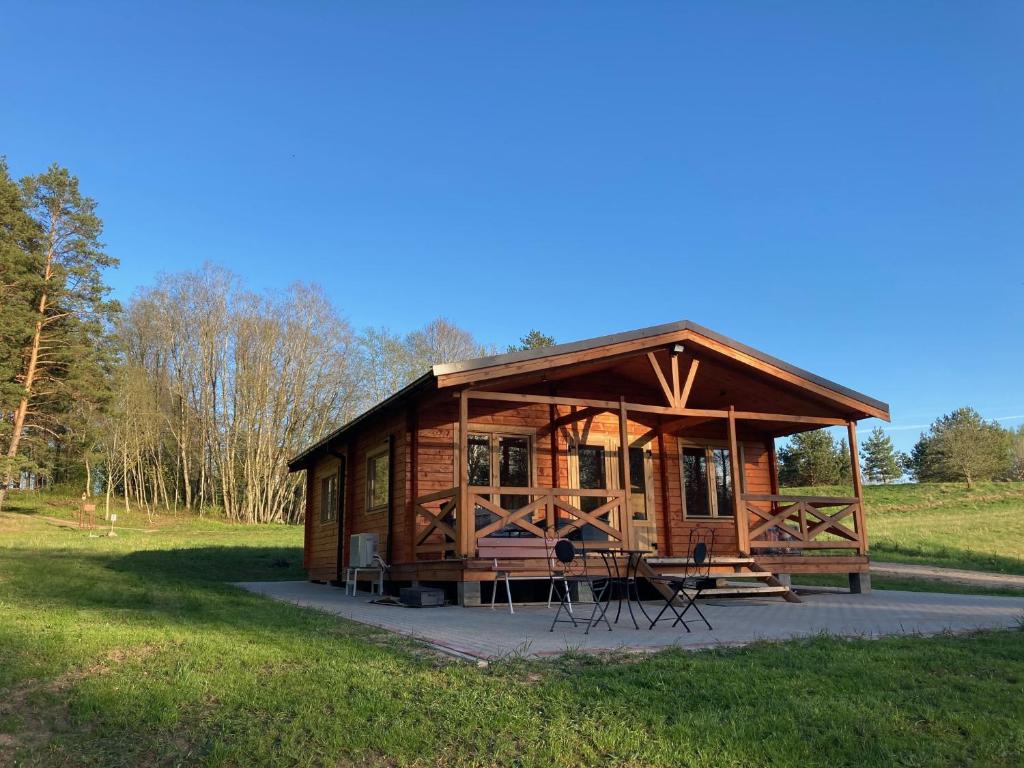 a log cabin with chairs and tables in a field at Zarasaičio ežero sodyba in Magučiai