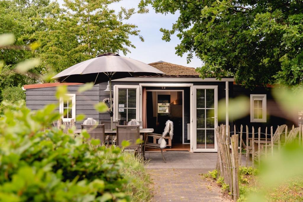 een klein huis met een paraplu en een tafel bij Reggechalet 6 persons adjusted in Zuna