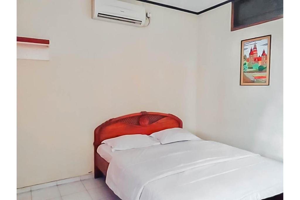 Schlafzimmer mit einem weißen Bett mit einem roten Kopfteil in der Unterkunft KoolKost Syariah @ Cibabat Cimahi in Cimindi