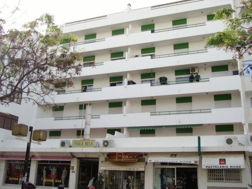 a large white building with green windows at Apartamentos Paula Bela by Garvetur in Quarteira