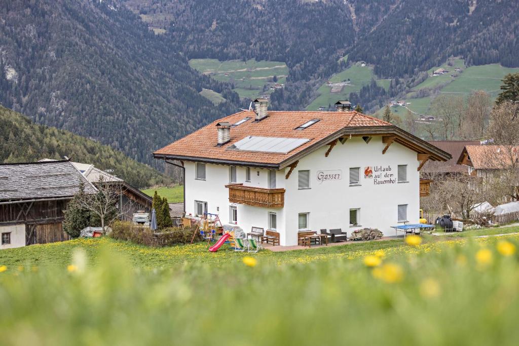 una casa blanca en una colina en un campo en Ferienwohnung Zirme Gasser, en Terento