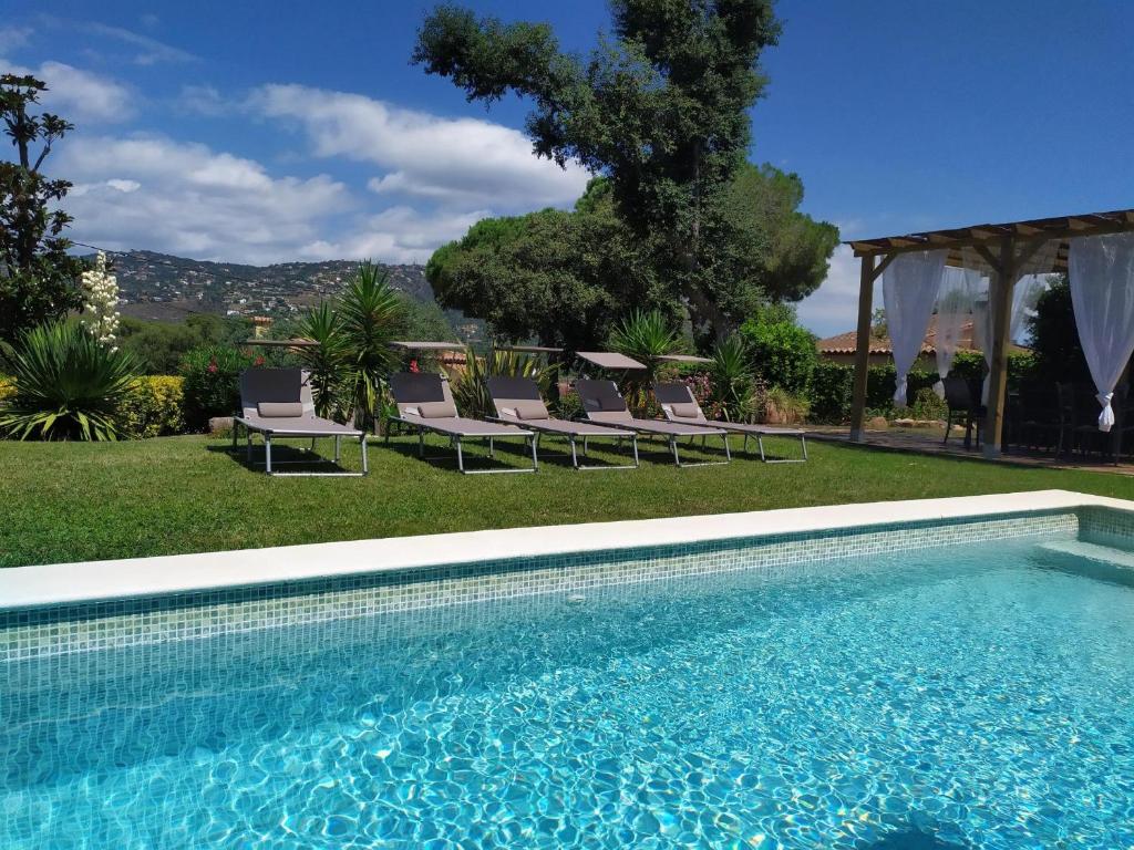 a swimming pool with chaise lounge chairs in a yard at Gramoia in S'Agaro