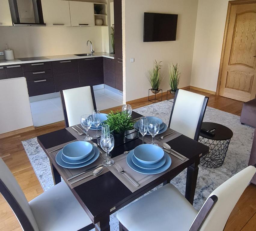 uma sala de jantar com uma mesa com pratos e copos de vinho em Rietumkrasta seaside apartment em Liepāja