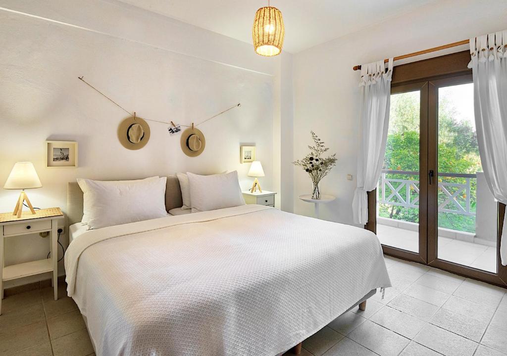 a white bedroom with a large bed and a window at Sanidiamonds in Sani Beach