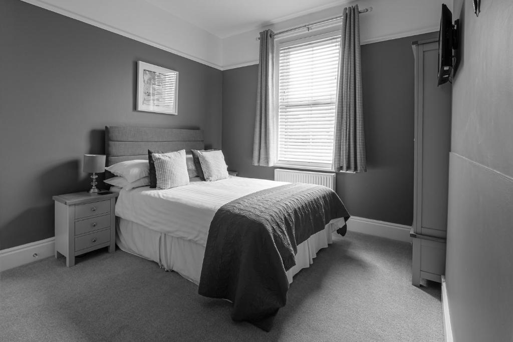 a black and white bedroom with a bed and a window at Millbrook Guest House in Swanage