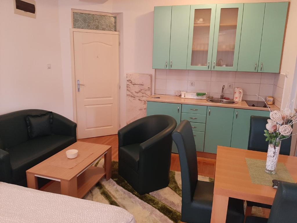 a kitchen with green cabinets and a table and chairs at Apartman Zivanovic1 in Banja Koviljača