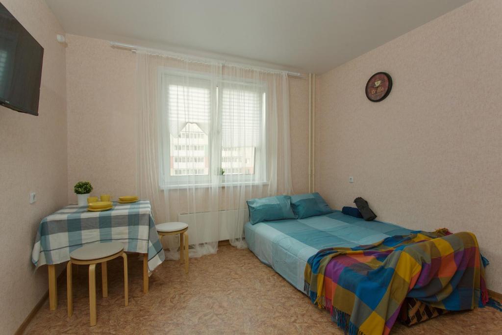 a bedroom with a bed and a table and a clock at СВЕЖО! Basic - Студия У Озера На Бурнаковской in Nizhny Novgorod