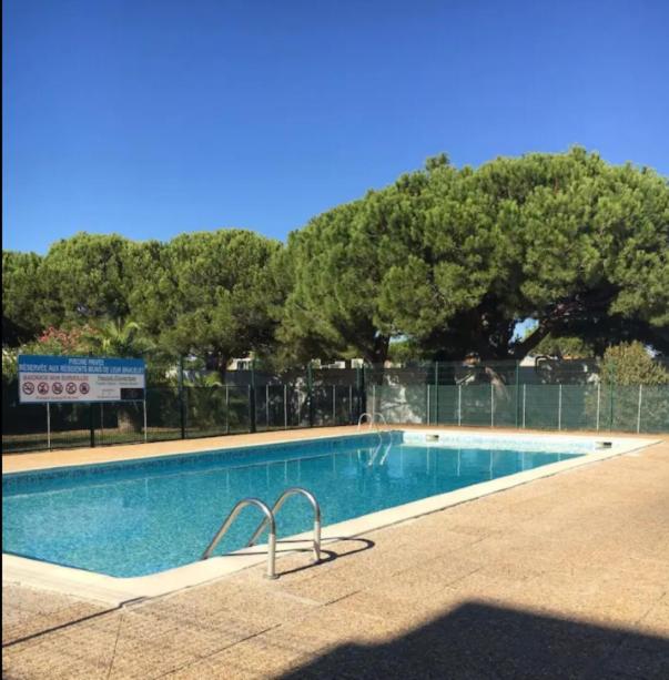 une grande piscine avec des arbres en arrière-plan dans l'établissement 2 pièces - Cabine et terrasse Véranda - GRAU DU ROI -, au Grau-du-Roi