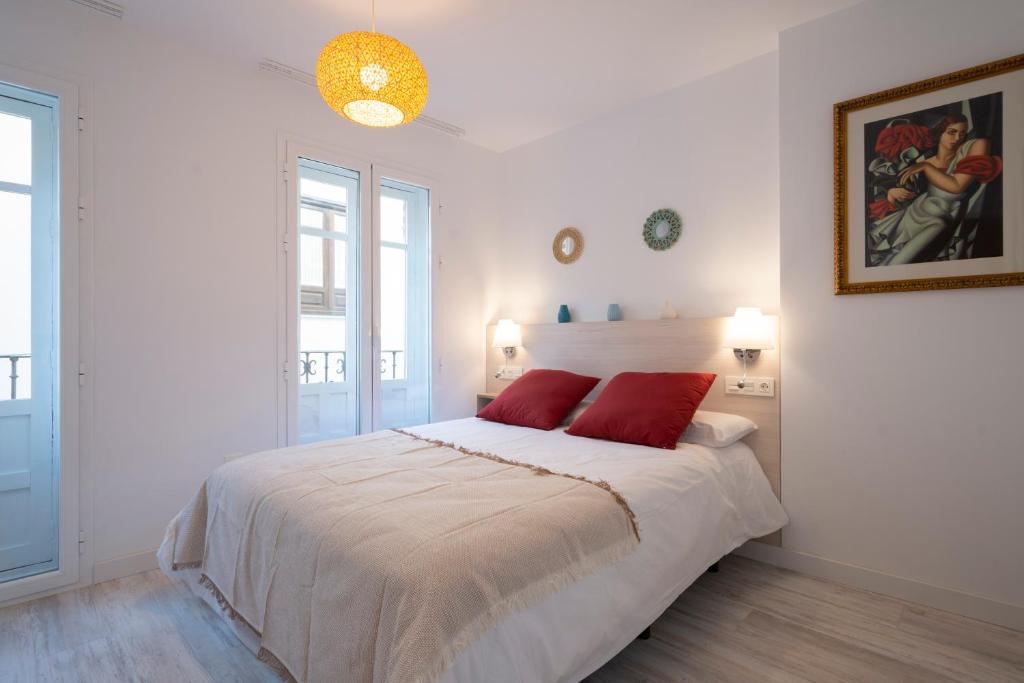Un dormitorio blanco con una cama grande con almohadas rojas en MOLINO CORTEZA EXCELENTE SEGUNDO Granada centro, en Granada