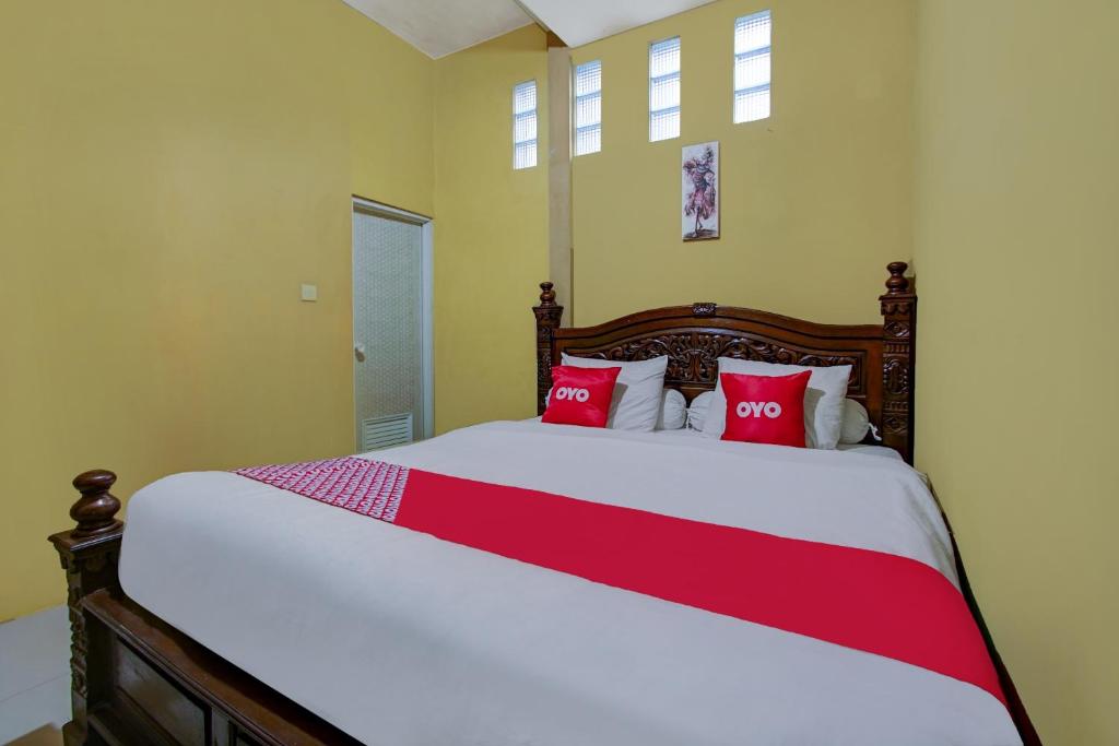 a bedroom with a large bed with red pillows at OYO 90061 Melati House Syariah in Malang