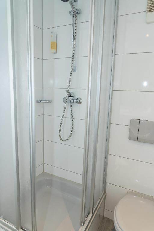 a shower with a glass door in a bathroom at Ringhotel Schlossberg in Neustadt