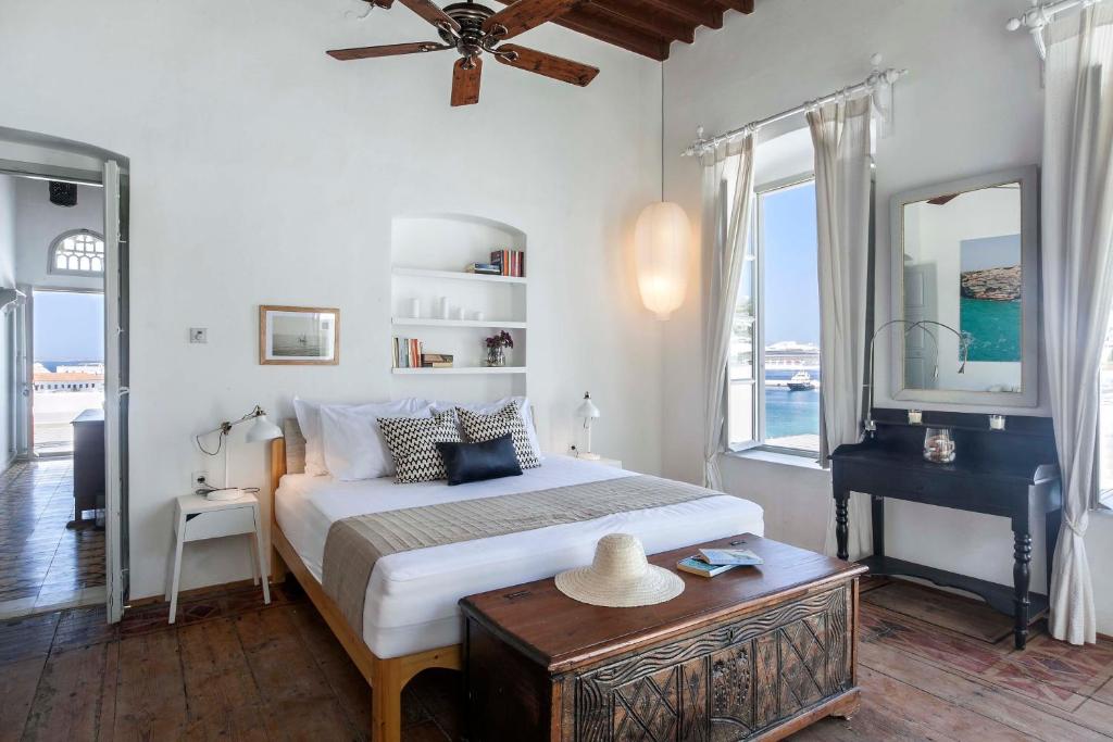 a bedroom with a bed and a table and windows at Josephine Mykonos Town Villa - 1882 in Mikonos