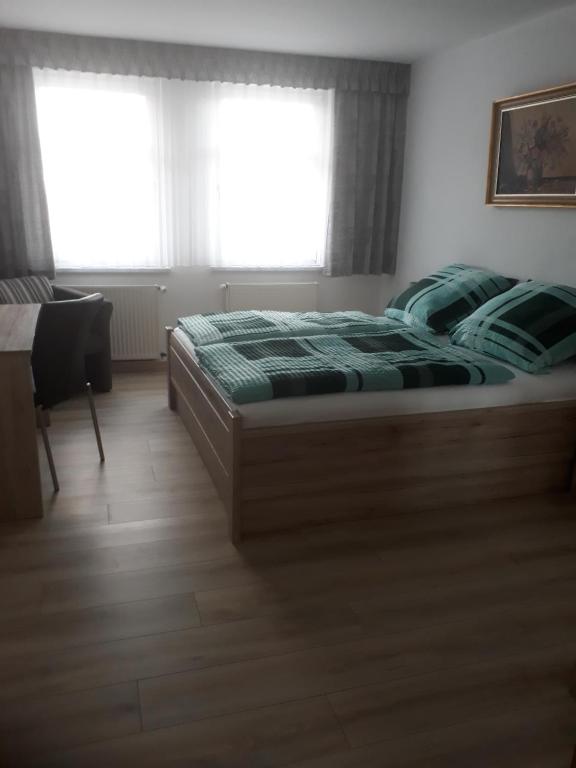 een slaapkamer met een bed met een groen dekbed en 2 ramen bij Ferienwohnung Steinweg 28 in Quedlinburg
