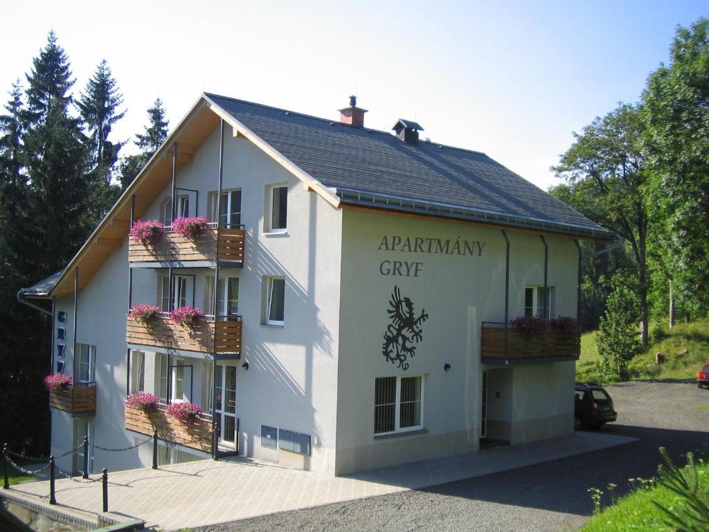 a white building with flower boxes on the windows at Apartmány Gryf Harrachov in Harrachov