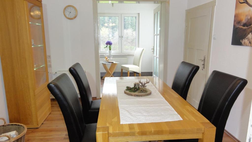 een eetkamer met een houten tafel en zwarte stoelen bij FeWo Obstfelderschmiede in Mellenbach-Glasbach