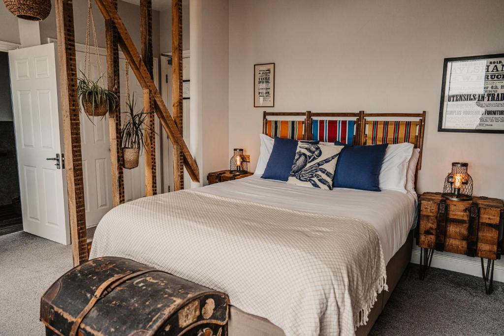 a bedroom with a large bed with blue pillows at The Ship Inn in Mundesley