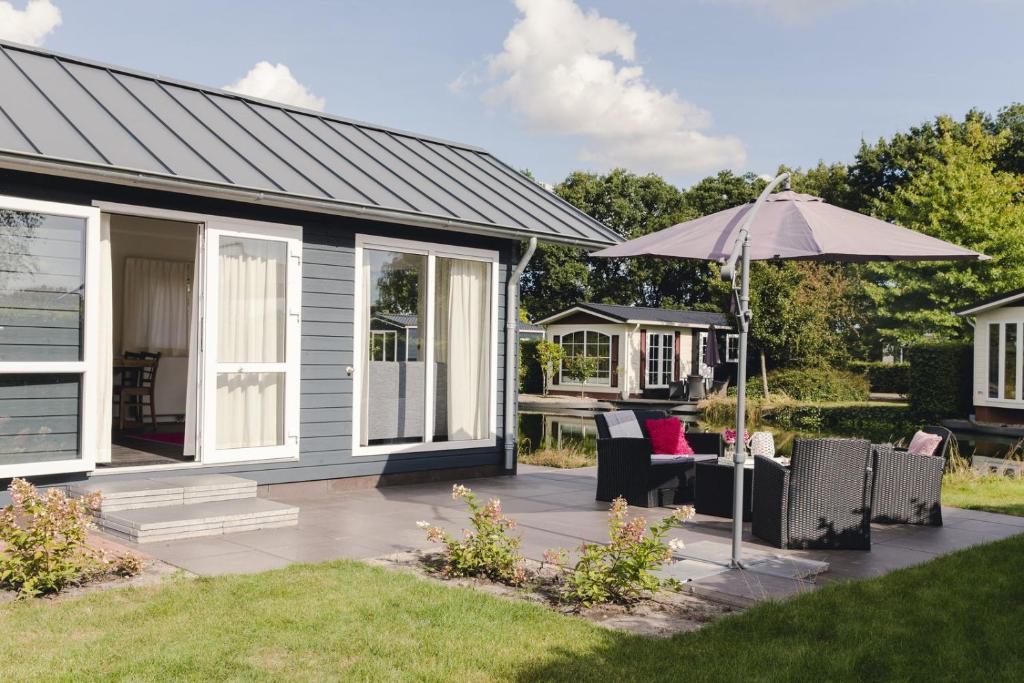 ein Haus mit einer Terrasse mit einem Sonnenschirm in der Unterkunft Salland 4 persons in Rijssen