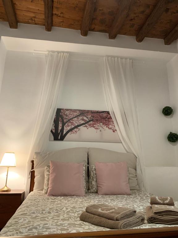 a white bed with pink pillows and a canopy at Althea Garden House in Hydra