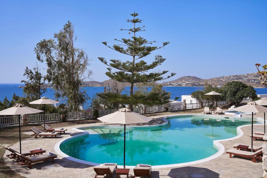 una piscina con sillas y sombrillas junto al océano en High Mill Paros Hotel, en Parikia