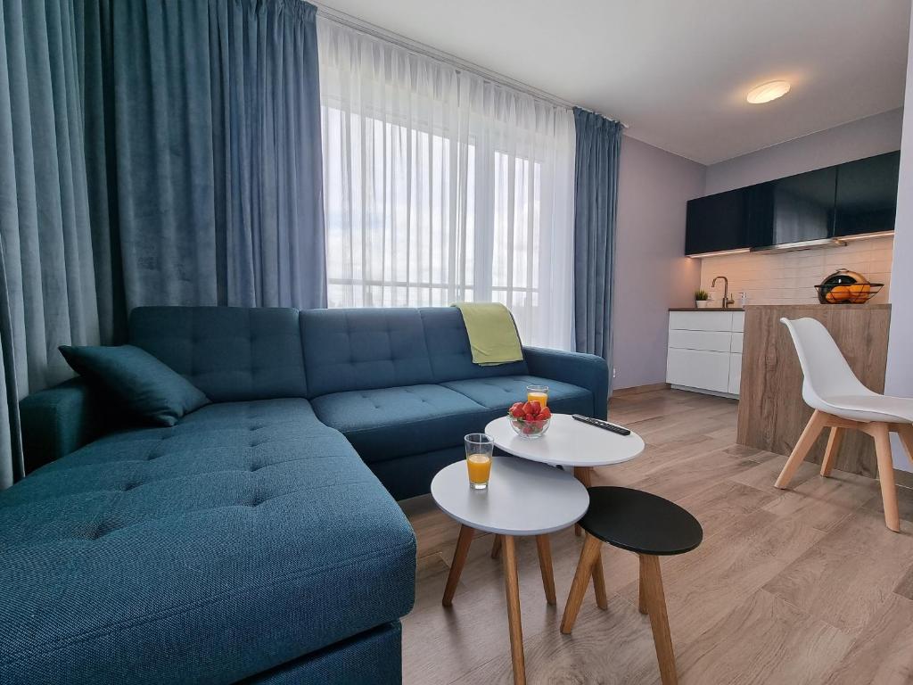 a living room with a blue couch and a table at Apartament Rodzinny - 365PAM in Gąski