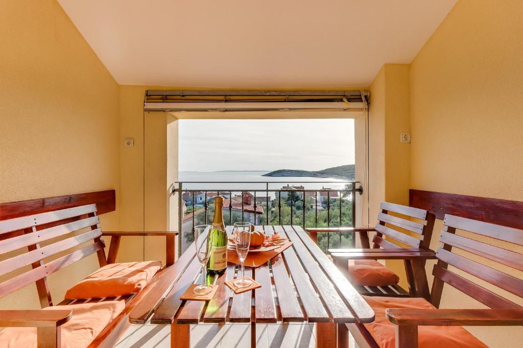 een tafel met twee stoelen en uitzicht op de oceaan bij Apartmani Tanja in Martinšćica