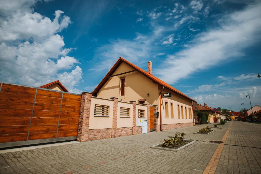 a house with a wooden fence next to a street at Németh Apartmanházak in Mórahalom