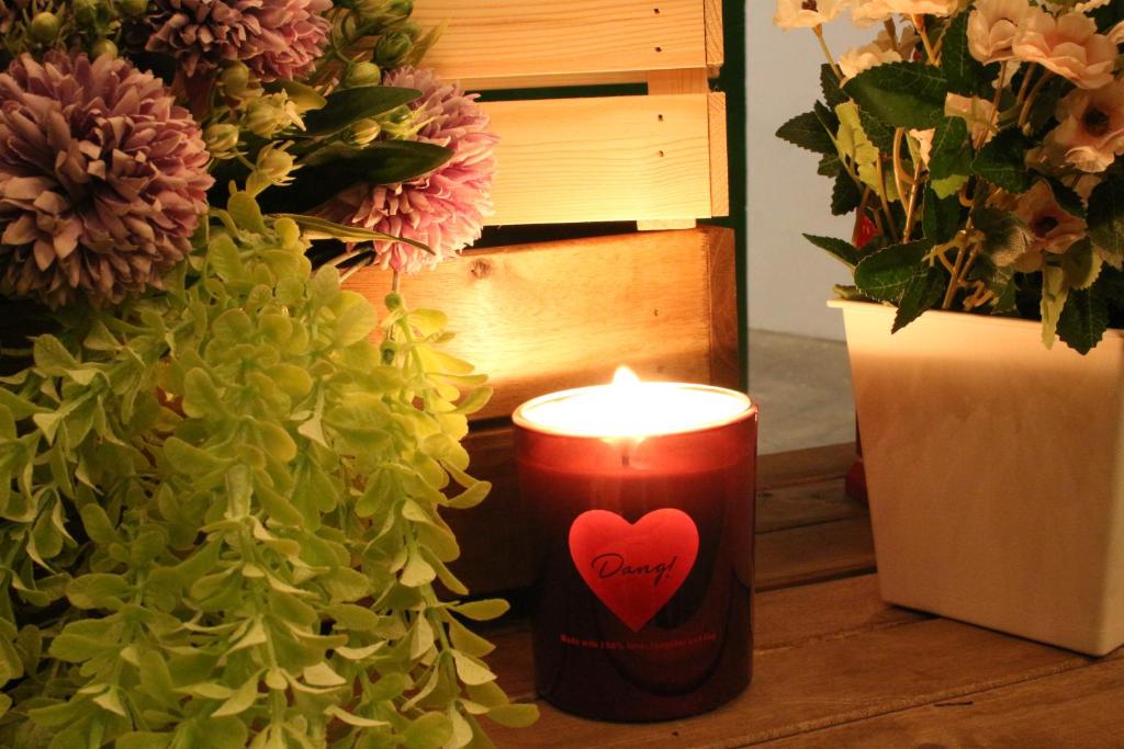a candle with a heart on it next to flowers at T-Life Hostel in Longjing