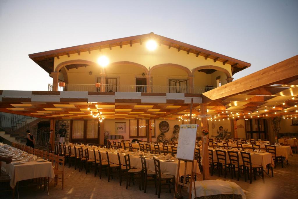 un restaurant avec des tables et des chaises en face d'un bâtiment dans l'établissement Agriturismo da Lino AGRIPIZZA, à Samughèo