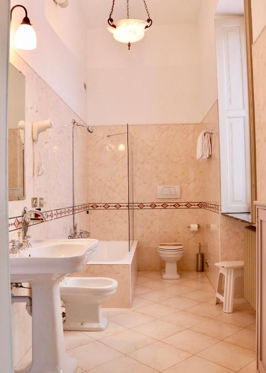 a bathroom with a sink and a tub and a toilet at Hotel Du Parc in Stresa