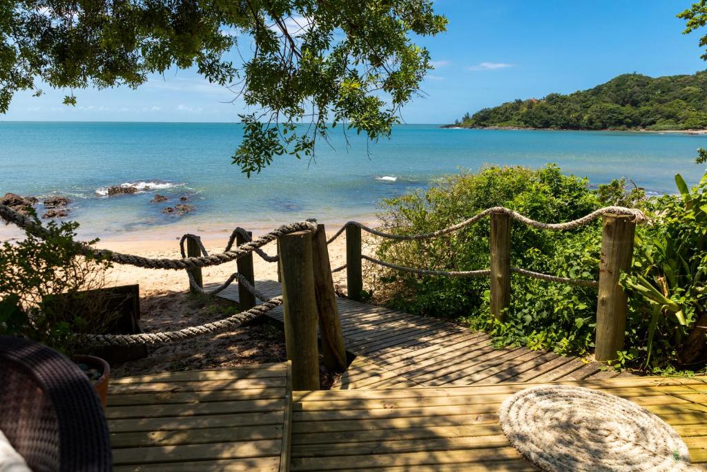 a wooden path leading to a beach with a fence at Pousada Ponta da Vigia in Penha