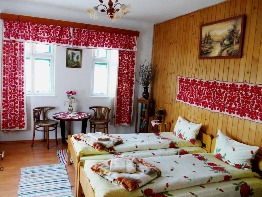 una camera con due letti, un tavolo e finestre di Kristaly vendeghaz a Rimetea