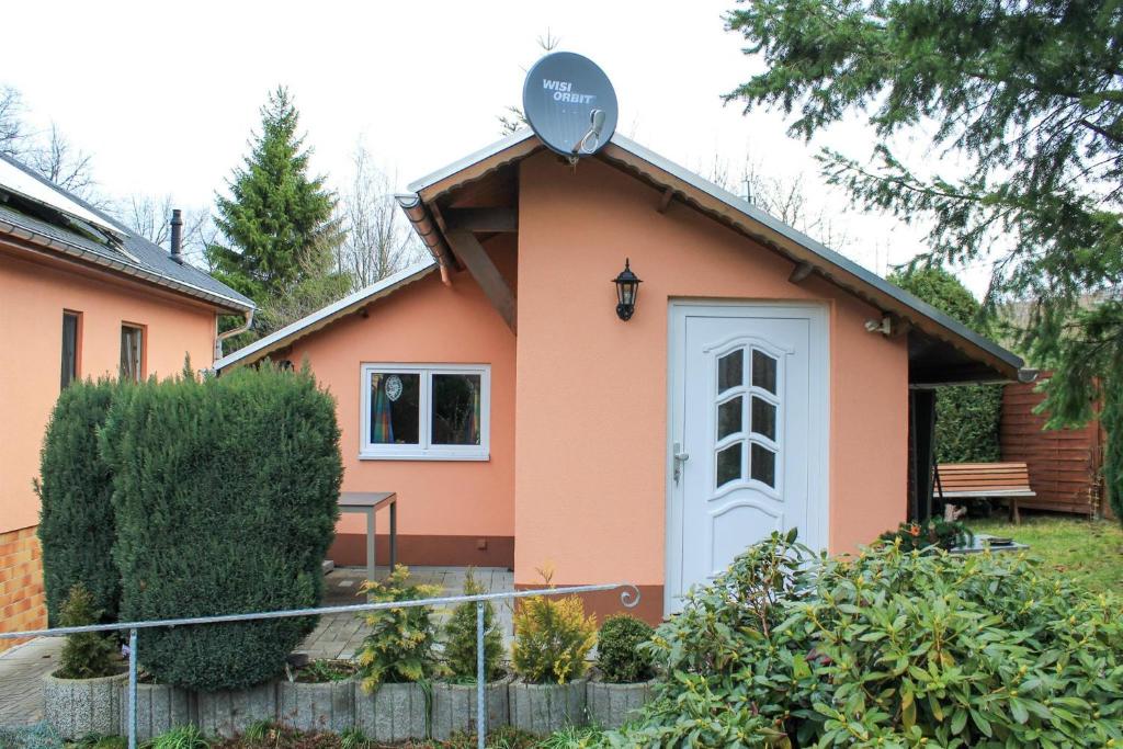 Ferienhaus Oertel في أنابيرغ-بوخهولتس: منزل وردي صغير مع باب أبيض