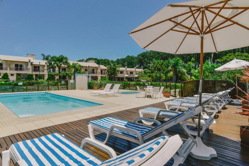 a group of lounge chairs and an umbrella next to a pool at Villa Oliva Residence in Florianópolis