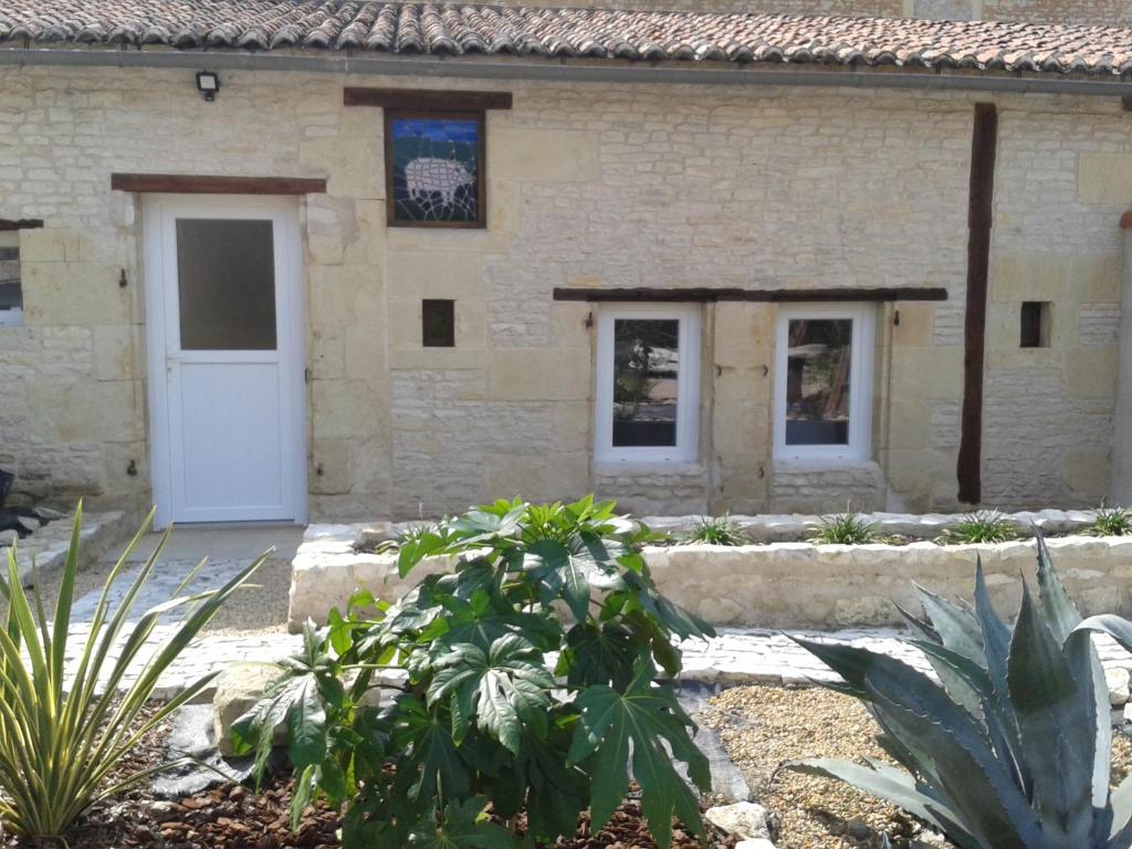 ein Gebäude mit einer weißen Tür und einigen Pflanzen in der Unterkunft The Piggeries at La Maison Tumtum Arbre in Loudun