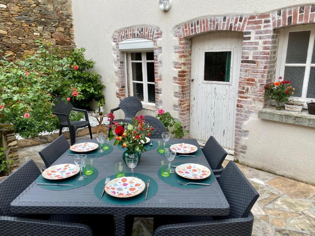 una mesa negra con platos y flores. en La Maison du Bonheur - Grande maison de vacances classée 4 étoiles, en Le Boupère