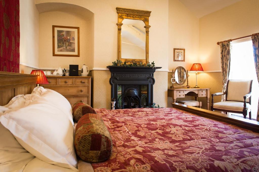 a bedroom with a bed with a fireplace and a mirror at Victoria House Room Only Accommodation in Caernarfon