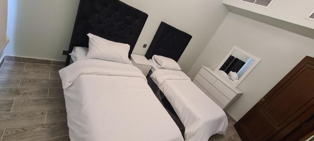 two beds in a room with white sheets and pillows at درة العروس كورال بيتش فيلا in Durat Alarous