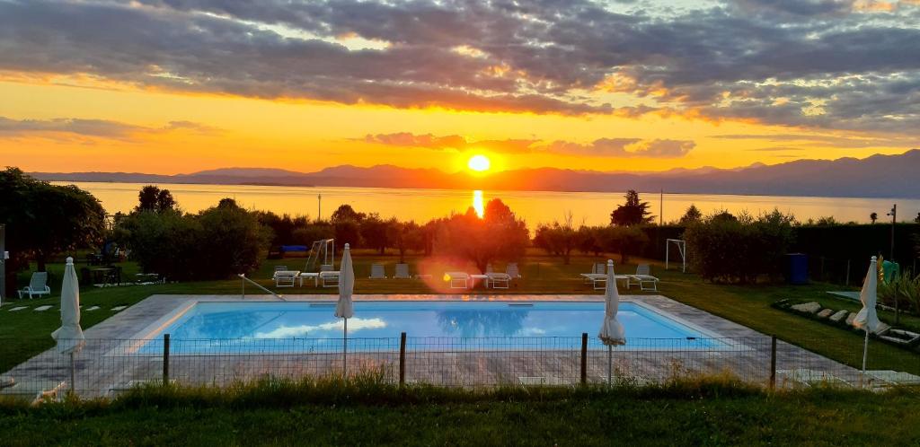 a swimming pool with the sunset in the background at Agriturismo Al-Bor in Lazise