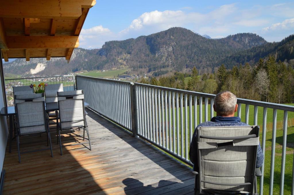 Ein Mann auf einem Balkon mit Bergblick in der Unterkunft Ankirchen Apartments in Vorderthiersee