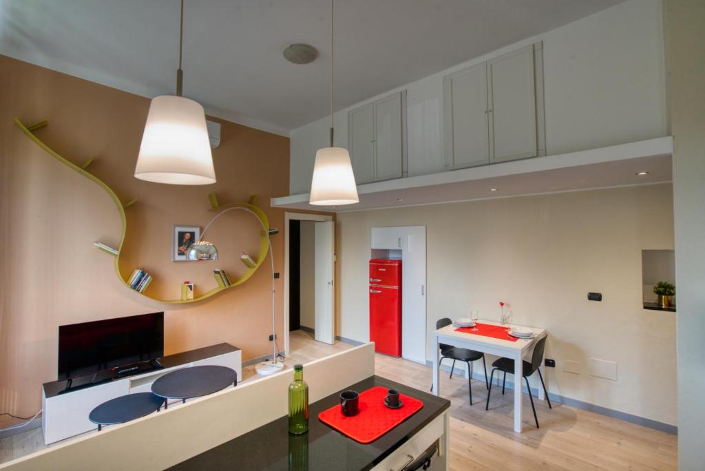 sala de estar con mesa roja y cocina en CaseOspitali - GALILEO nuovo bilocale vicino al Policlinico Monza - Self Check-In, en Monza