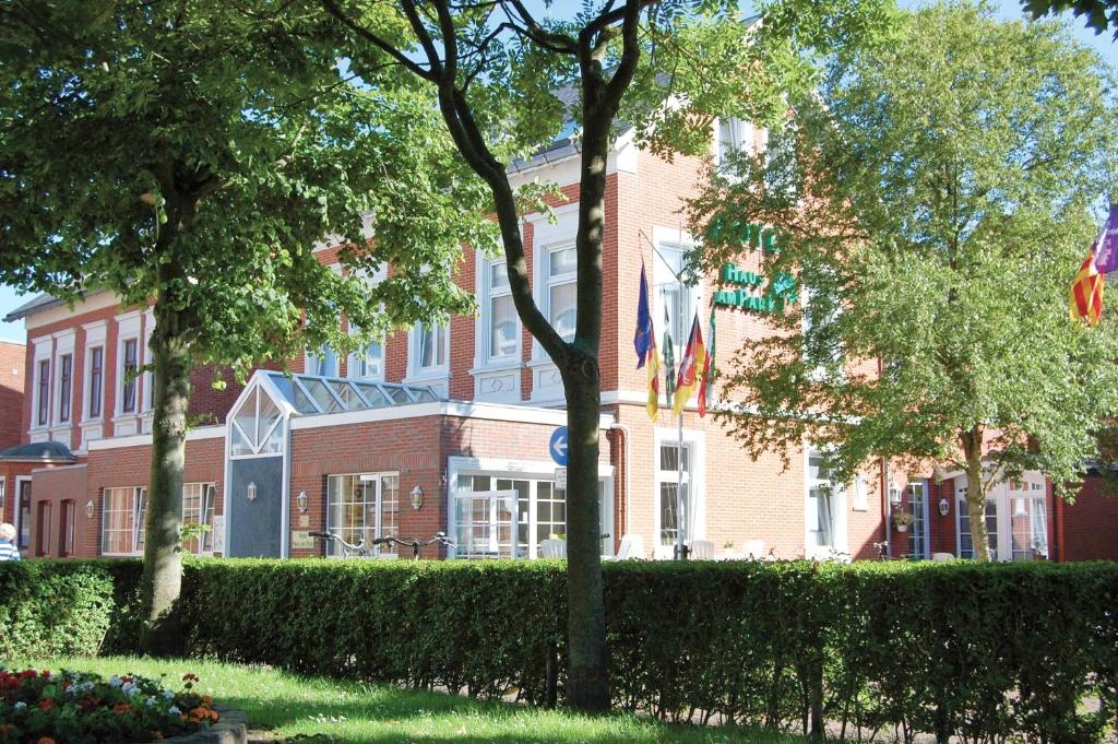 um edifício de tijolos vermelhos com bandeiras à frente em Hotel Haus am Park em Borkum