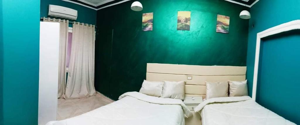 zwei Betten in einem Zimmer mit grüner Wand in der Unterkunft My place agata Hostel in Kairo